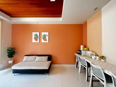 a bedroom with orange walls and a bed and a table at Smile Residence at Kaset-Sena in Ban Yang