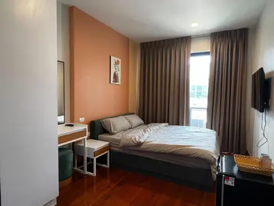 a bedroom with a bed and a desk and a window at Smile Residence at Kaset-Sena in Ban Yang