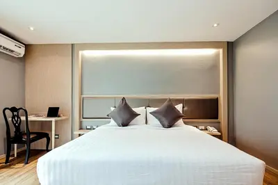 a bedroom with a large white bed and a desk at Three Sukhumvit Hotel - SHA Plus Certified in Bangkok