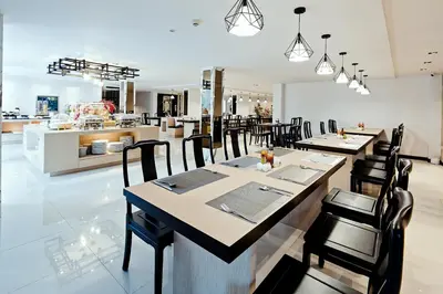 a restaurant with tables and chairs and a kitchen at Three Sukhumvit Hotel - SHA Plus Certified in Bangkok