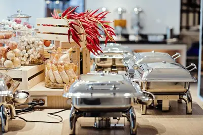 a buffet line with trays of food on a table at Three Sukhumvit Hotel - SHA Plus Certified in Bangkok