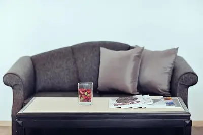 a coffee table with a glass on top of a couch at Three Sukhumvit Hotel - SHA Plus Certified in Bangkok
