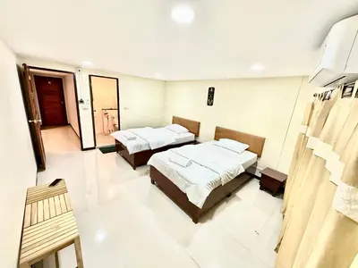 a hotel room with two beds and a room with two chairs at Baan at Khaosan Hostel in Bangkok