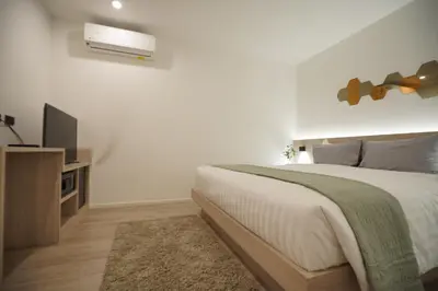 a white bedroom with a bed and a television at E11 Hotel - BTS Punnawithi in Amphoe Phra Khanong