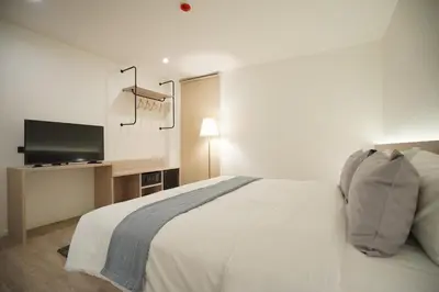 a bedroom with a white bed and a flat screen tv at E11 Hotel - BTS Punnawithi in Amphoe Phra Khanong