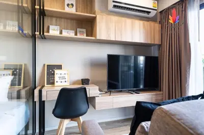 a living room with a tv and a desk with a chair at BTS S5 Surasak 900 meters near the Mekong River Pier Free Swimming Pool in Ferris Wheel Night Market Chinese Reception Bangkok Center in Lat Krabang