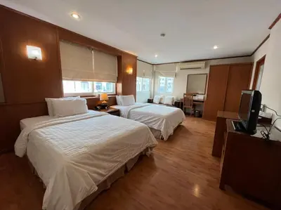 a hotel room with two beds and a television at Jhouse Thonglor in Khlong Toei