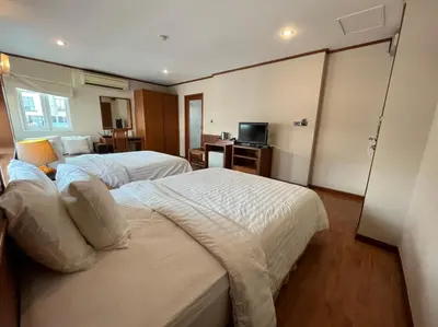 a hotel room with two beds and a television at Jhouse Thonglor in Khlong Toei