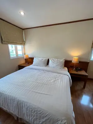a bedroom with a large white bed with two lamps at Jhouse Thonglor in Khlong Toei