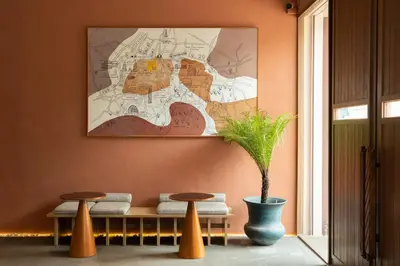 a bench with two stools and a painting on the wall at Stay Plus Hotel Bangkok in Bangkok
