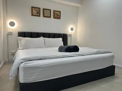 a bedroom with a large white bed with two lights at The White Den Sukhumvit 44 in Bangkok