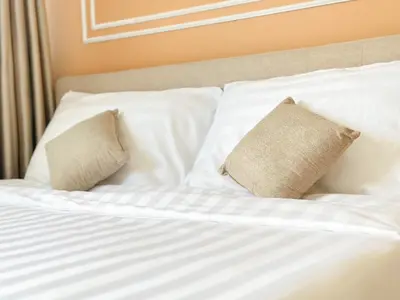a bed with white sheets and two pillows at NK hostel in Thung Si Kan