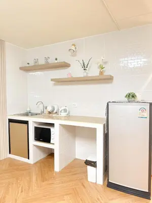 a white kitchen with a sink and a refrigerator at NK hostel in Thung Si Kan