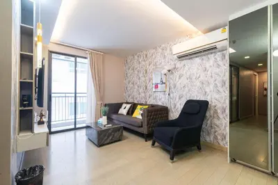 a living room with a couch and a chair at Dazzle Sukhumvit 7 by LeFoyer in Bangkok