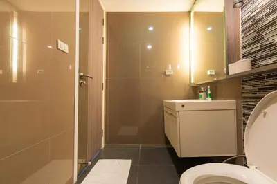 a bathroom with a toilet and a glass shower at Dazzle Sukhumvit 7 by LeFoyer in Bangkok