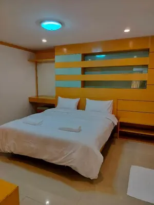 a bedroom with a large bed with a wooden headboard at Love mansion in Bangkok
