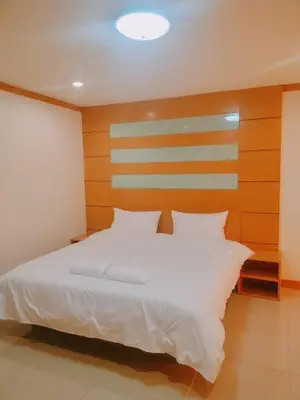 a bedroom with a white bed with a wooden headboard at Love mansion in Bangkok