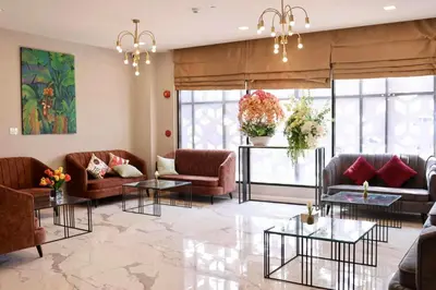 a living room with couches and tables and windows at Shewin de Bangkok in Ban Bang Bamru
