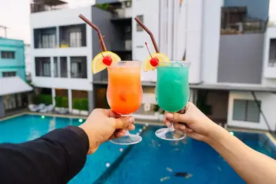 two people holding drinks in their hands near a pool at Shewin de Bangkok in Ban Bang Bamru