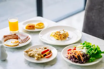 a table with plates of food and a glass of orange juice at Shewin de Bangkok in Ban Bang Bamru
