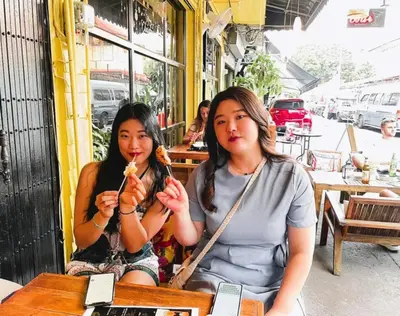 two women sitting at a table eating food at Back Home Backpackers Hostel in Bangkok