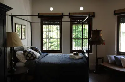 a bedroom with a bed and two windows at The Bhuthorn Bed & Breakfast in Bangkok