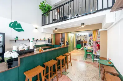 a restaurant with a green bar with wooden stools at PICCOLO SUKHUMVIT HOSTEL- Self check-in after 6 pm in Bangkok