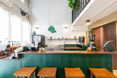 a kitchen with wooden tables and a counter with chairs at PICCOLO SUKHUMVIT HOSTEL- Self check-in after 6 pm in Bangkok