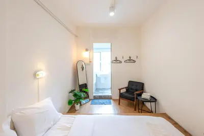 a bedroom with a bed and a chair and a mirror at PICCOLO SUKHUMVIT HOSTEL- Self check-in after 6 pm in Bangkok