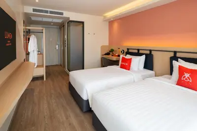 two beds in a hotel room with red pillows at Lumen Bangkok Udomsuk Station in Bangkok