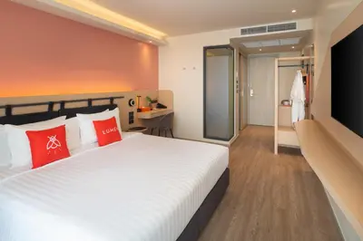 a bedroom with a large white bed with red pillows at Lumen Bangkok Udomsuk Station in Bangkok