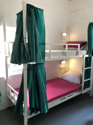 a bedroom with two bunk beds with green curtains at PLOY Hostel in Bangkok