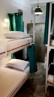 a room with three bunk beds with green curtains at PLOY Hostel in Bangkok