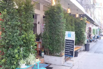 a sign in front of a building with potted plants at PLOY Hostel in Bangkok
