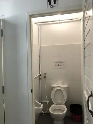 a small bathroom with a toilet and a shower at PLOY Hostel in Bangkok