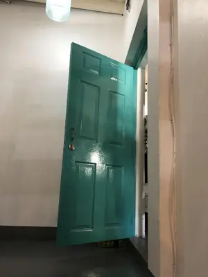 a green door in a room with a wall at PLOY Hostel in Bangkok