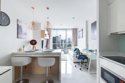 a white kitchen with a desk and chairs at The Pinnacle Sukhumvit 11 by LeFoyer in Bangkok
