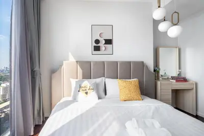a bedroom with a large white bed with yellow pillows at The Pinnacle Sukhumvit 11 by LeFoyer in Bangkok