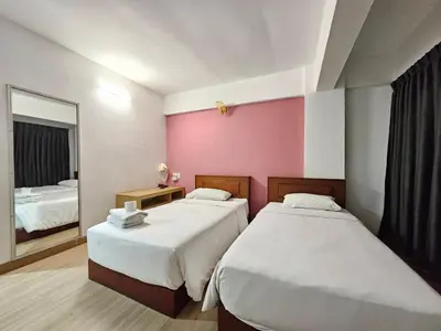 a hotel room with two beds and a mirror at Crown BTS Nana Hotel in Bangkok