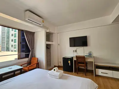 a hotel room with a bed and a desk and a tv at Crown BTS Nana Hotel in Bangkok