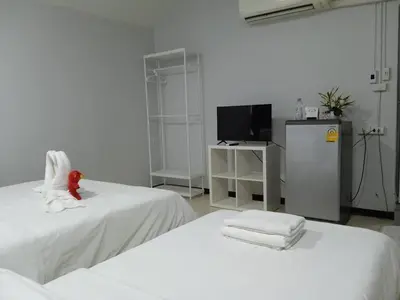 a white room with two beds and a television at NK Guesthouse 1 in Khlong Toei