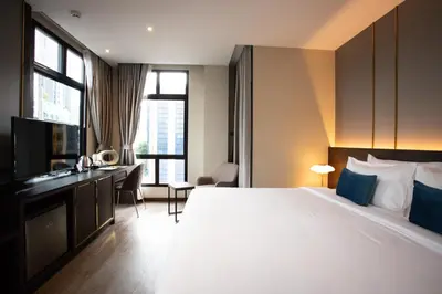 a hotel room with a large bed and a desk at SAM E Hotel Bangkok Sathorn in Bangkok