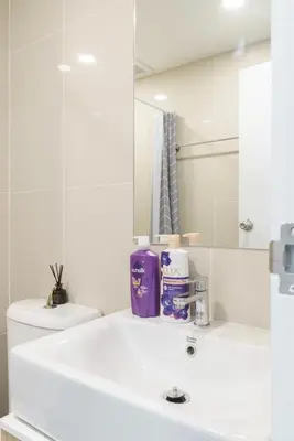 a white bathroom with a sink and a mirror at Sathon-Charoen Nakhon Condo in Bangkok