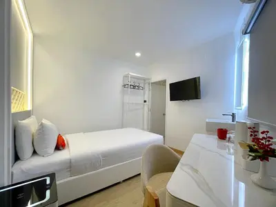 a white room with a bed and a table at Arawana Express Sukhumvit 22 in Bangkok