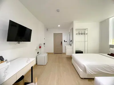 a white bedroom with two beds and a flat screen tv at Arawana Express Sukhumvit 22 in Bangkok