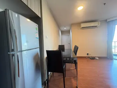 a dining room with a table and a refrigerator at Rama9 Luxe Suites in Bangkok