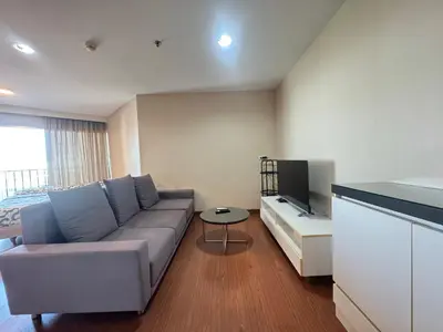 a living room with a couch and a tv at Rama9 Luxe Suites in Bangkok