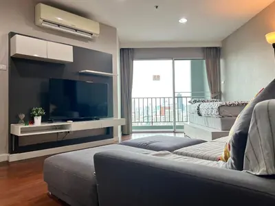 a living room with a couch and a flat screen tv at Rama9 Luxe Suites in Bangkok