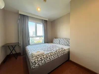a small bedroom with a bed with a window at Rama9 Luxe Suites in Bangkok