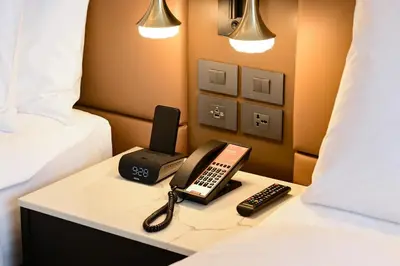 a room with a bed with a phone and remote controls at Madi Paidi Bangkok, Autograph Collection in Bangkok